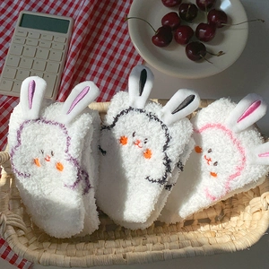 Close-up of fluffy white coral fleece socks with cute rabbit ears in a woven basket