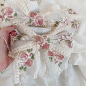 Dettaglio di calze Lolita in pizzo con ricamo a rose rosa e fiocco decorativo dolce