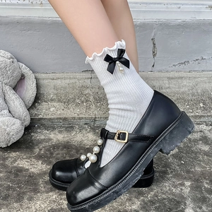 Chaussettes blanches à volants et nœuds avec chaussures Mary Jane noires à brides perlées