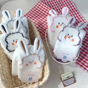 Close-up of fluffy coral fleece socks with 3D bunny ears and cute embroidery