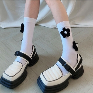 Gros plan de chaussures Mary Jane à plateforme noir et blanc avec chaussettes à fleurs