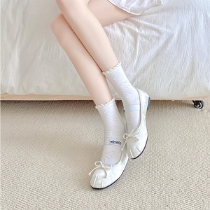 Detail of white satin Mary Jane flats with bow and butterfly pattern lace socks