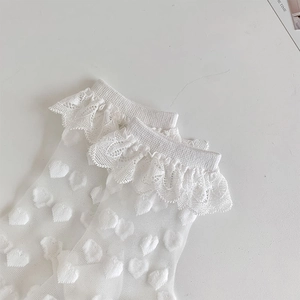 Close-up of white lace socks with heart patterns and sheer mesh fabric in Lolita style