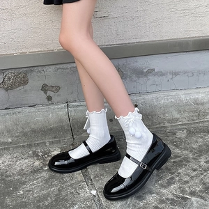 Détail de chaussures Mary Jane noires avec chaussettes blanches à volants et nœud