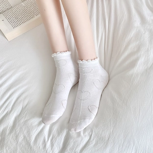 Close-up of white women's socks featuring ruffle edges and delicate heart jacquard patterns