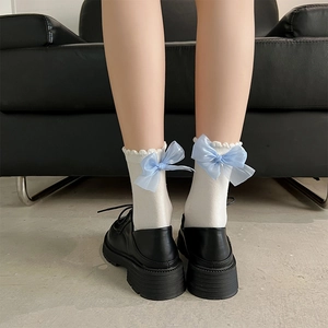 Vue détaillée de chaussettes blanches à volants avec nœud en organza bleu clair et chaussures