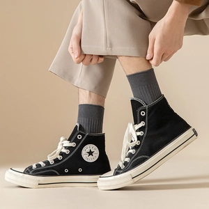Close-up of black mid-calf ribbed socks paired with high-top canvas sneakers for men