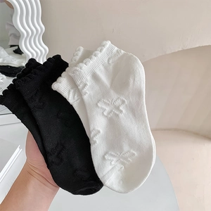 Close-up of black and white frilly socks with 3D butterfly jacquard and ruffles