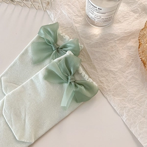 Détail de chaussettes en tricot vert clair avec bord à volants et nœud en organza