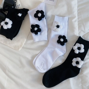 Détail de fleurs tricotées en 3D sur des chaussettes en coton noir et blanc