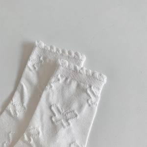 Detail of white cotton socks with butterfly jacquard pattern and ruffled edges