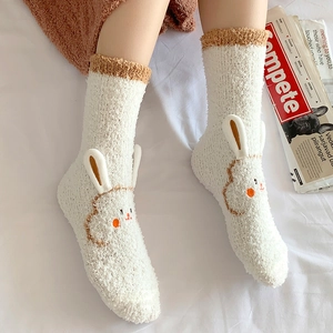 Close-up of thick coral fleece socks featuring 3D rabbit ears and soft embroidery detail