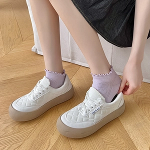 White quilted sneakers with gum sole paired with sweet lace ankle socks on wood floor