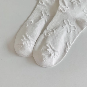 Close-up of white cotton socks featuring delicate 3D bow texture and knit details