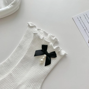 Vue détaillée de chaussettes Lolita blanches avec volants, nœuds noirs et perles