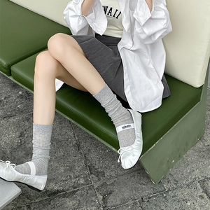 Gros plan sur des ballerines en satin blanc avec nœud et sangle logo sur chaussettes