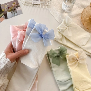 Détail de chaussettes pastel avec grands nœuds en satin dans un décor lifestyle