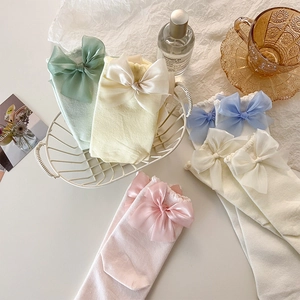 Vue détaillée de chaussettes en coton pastel avec de grands nœuds doux dans un panier