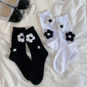 Détail de chaussettes mi-mollet avec fleurs au crochet 3D faites main en noir et blanc