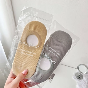 Close-up of khaki and gray thin no-show socks in transparent zipper packaging