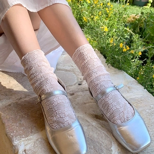 Pink lace ruffle socks paired with silver square-toe Mary Jane shoes in a garden setting