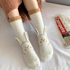 Detailed macro view of plush coral fleece socks with 3D cartoon bunny ears design