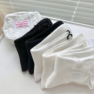Gros plan de chaussettes Lolita avec nœuds en satin blanc en noir et blanc