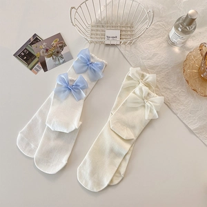 Détails de chaussettes côtelées crème avec des ornements élégants en nœuds de mousseline