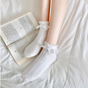 Détails de chaussettes blanches à volants et tricot ajouré sur fond de lit douillet
