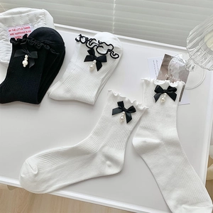 Détail de chaussettes à volants avec nœuds en soie et perles sur coton côtelé doux