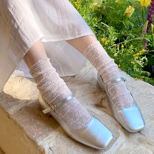 Close-up of silver Mary Jane shoes paired with light pink lace ruffled slouch socks