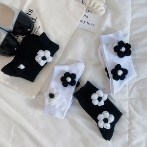 Vue à plat de chaussettes en coton noir et blanc avec détails de fleurs au crochet en 3D