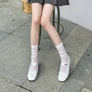 Détail de chaussettes en coton blanc côtelé portées avec des ballerines en satin
