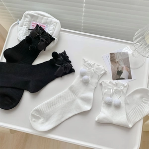 Détail de chaussettes style Lolita avec volants, nœuds et pompons décoratifs