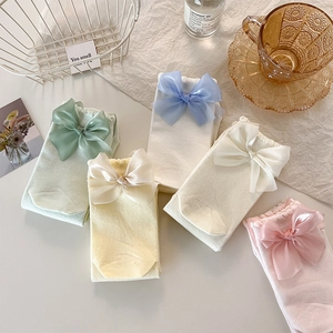 Détail de chaussettes pastel avec grands nœuds en mousseline sur fond décoratif