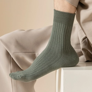 Close-up of olive green ribbed cotton dress socks showing vertical texture and wide cuffs