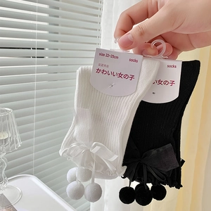 Détails des nœuds en ruban et pompons sur chaussettes hautes noires et blanches