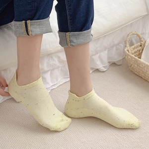 Pale yellow low-cut boat socks with colorful speckles for women in home setting