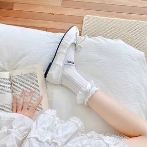 Gros plan de chaussettes en dentelle blanche avec nœud et ballerines souples