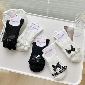 Détail de chaussettes Lolita avec nœuds, perles, dentelle et pompons en fourrure