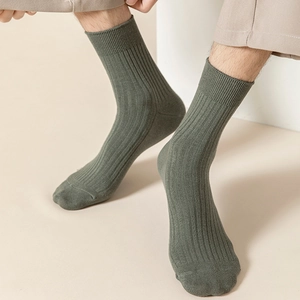 Detailed view of men's dark green vertical ribbed crew socks on model in minimalist setting