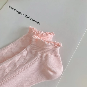 Close-up of light pink lace socks with geometric texture and ruffled cuffs detail