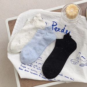 Detailed view of three pairs of speckled cotton boat socks in white, blue, and black colors