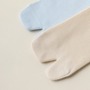 Detail of ribbed knit tabi socks showing split-toe seam in light blue and beige colors