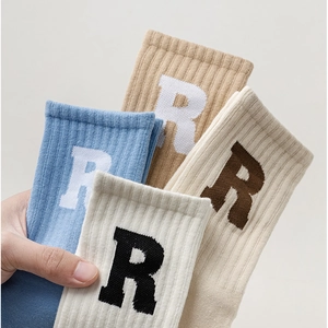 Detailaufnahme der Rippstruktur und R-Buchstaben-Jacquard auf bunten Yoga-Socken