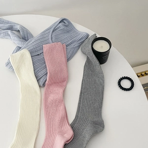 Dettaglio di calze al polpaccio in maglia a coste crema, rosa, grigie e top blu