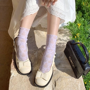 Detail of off-white Mary Jane shoes with ribbon bows and purple lace socks