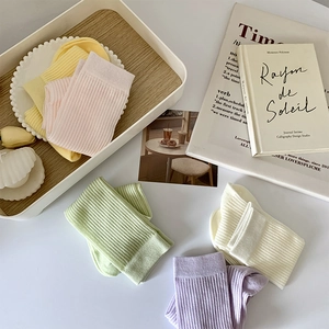 Gros plan de chaussettes en coton pastel avec texture côtelée et maille ajourée