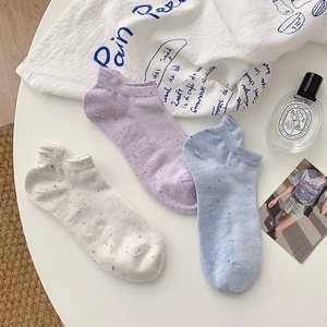 Close-up of three pairs of speckled cotton low-cut socks in white, purple, and blue colors