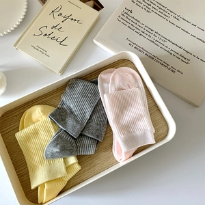 Détail de chaussettes en coton côtelé aux couleurs pastel sur un plateau en bois esthétique